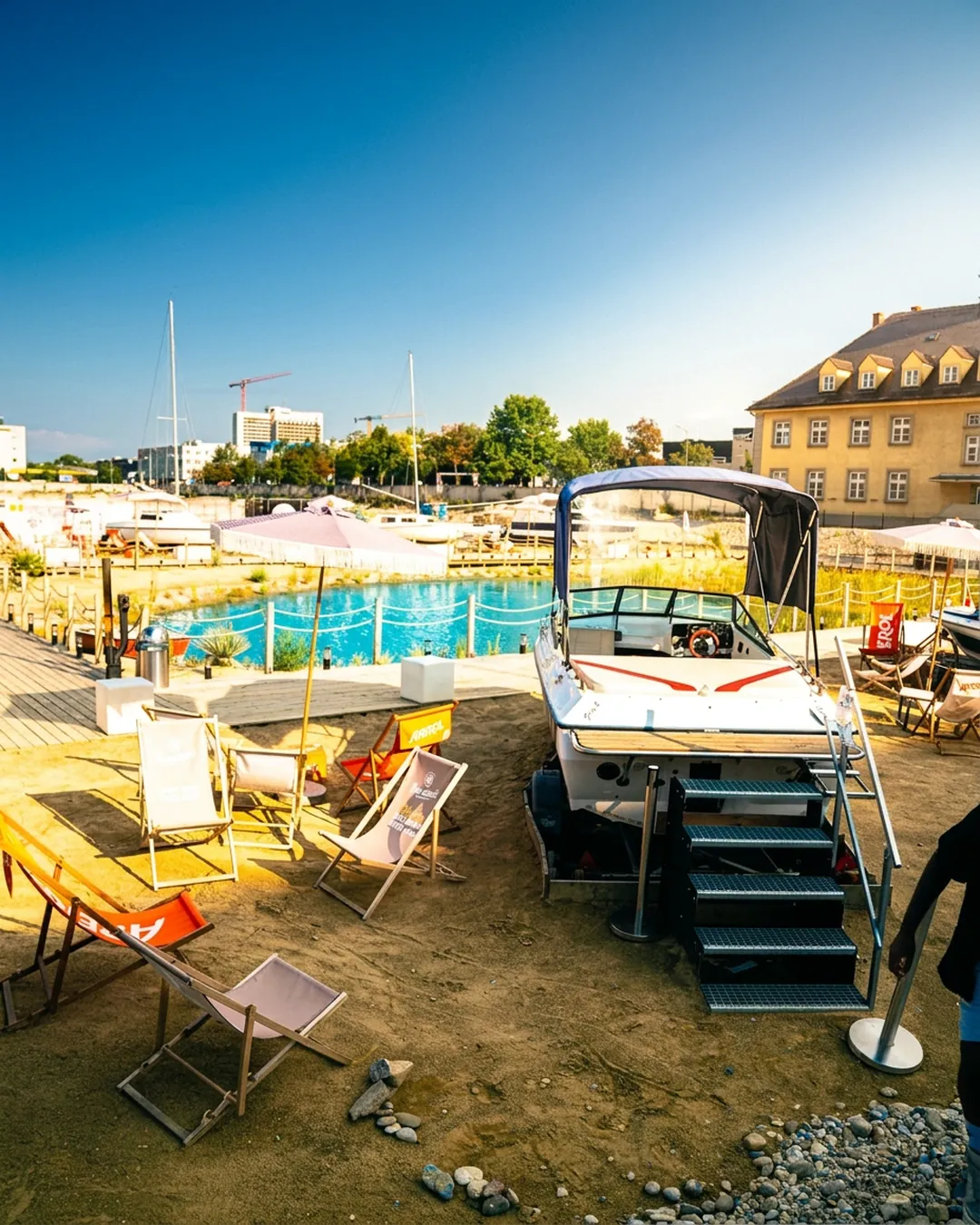 Liegestühle im Sand neben Bootlounge
